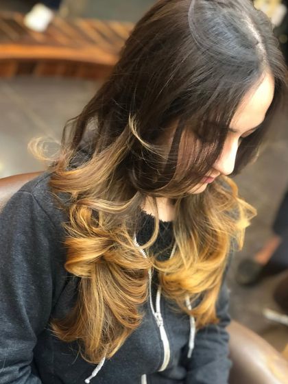The client is seen here admiring her new ombre color. This style is particularly effective at brightening up the overall look while keeping the roots dark for lower maintenance.