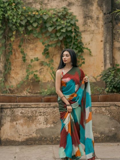 A full-length shot of the multi-color saree against a rustic wall.