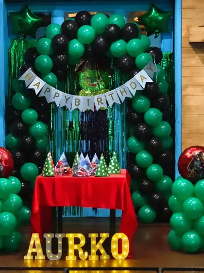 A green and black balloon arch setup for a 5th birthday party. This color scheme is perfect for themes like Avengers, Ben 10, or a general superhero party.