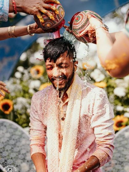 The traditional holy bath during the Haldi ceremony, capturing the groom's reaction in a dynamic splash of water.