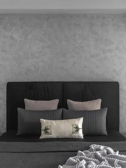 The daughter's bedroom uses a sophisticated palette of grey and black. Textured grey walls behind the bed add depth, while the simple black headboard creates an elegant and serene haven.