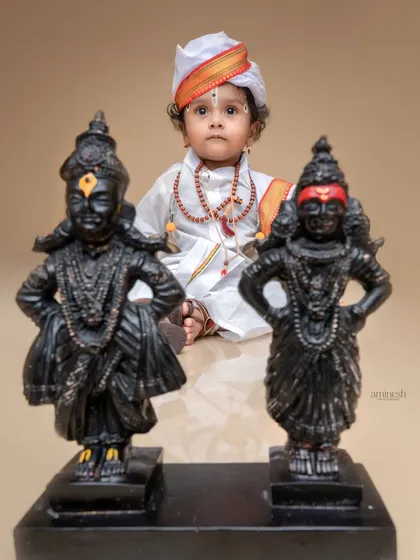 A creative composition with the baby Varkari sitting behind the idols of Vitthal and Rukmini. This perspective adds depth and a sense of reverence to the themed photograph.