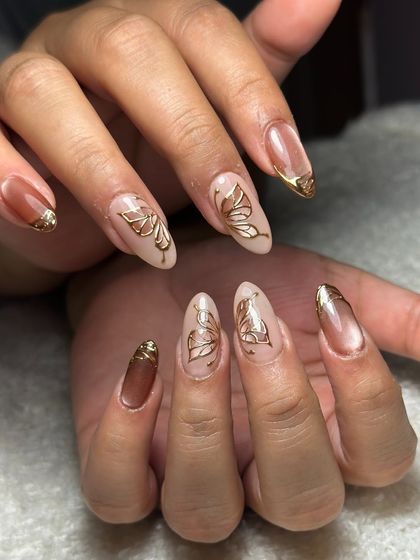 A little butterfly moment. This elegant set features hand-drawn golden butterflies on a nude base, with cat-eye and gold chrome French tips.