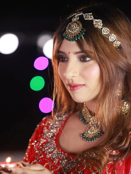 Another portrait from the Diwali series, capturing the model holding a lit diya. The colorful lights in the background create a festive and celebratory atmosphere.