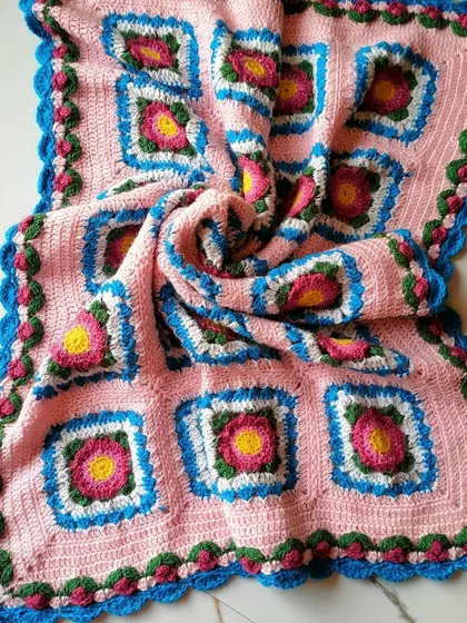 The Lydia blanket is a piece I'm very proud of, featuring delicate floral squares set against a soft pink background. I finished it with a detailed rosebud border, making it a truly special handmade blanket for adding warmth and charm to any home.