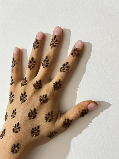 A chic and modern design with small, scattered leafy sprigs covering the back of the hand and fingers.