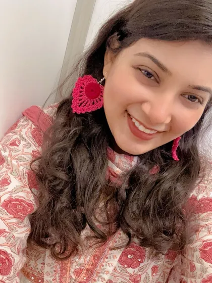 This is how my large, heart-shaped crochet earrings look when worn. They are handmade, super lightweight, and add a fun pop of bright pink to any outfit, making them a perfect statement piece.