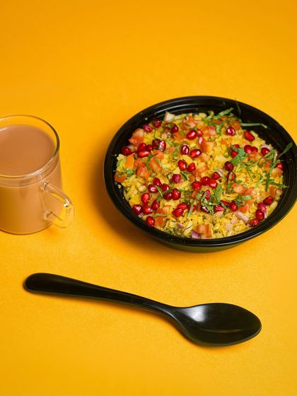 A simple, appealing shot of poha and chai against a bright yellow background. This composition is clean, colorful, and makes you crave a good breakfast.