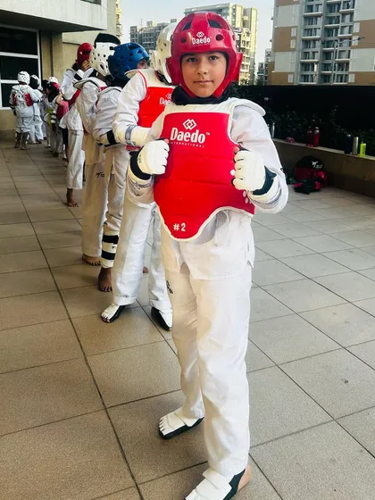 A student in red protective gear, focused and prepared for his match.