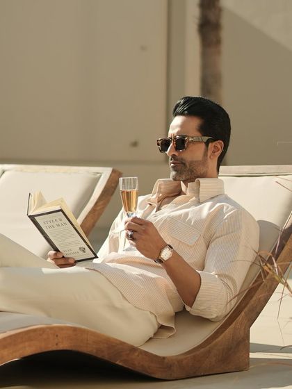 A full view of the pinstripe shirt in a luxurious poolside setting, reinforcing the sophisticated, relaxed lifestyle our brand embodies.