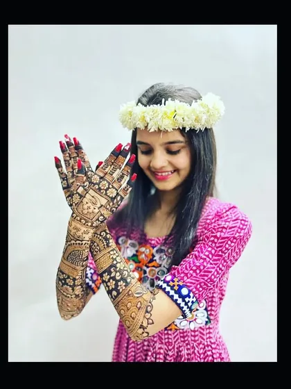 A lovely pose from a happy bride, showing off the symmetry and detail of her full bridal mehndi.