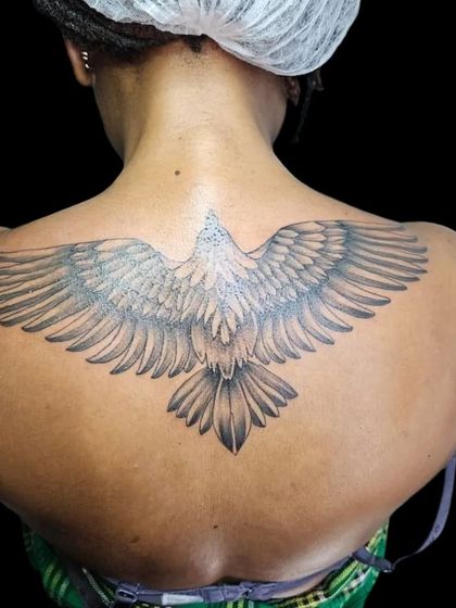A large eagle tattoo with wings spread across the upper back. This design symbolizes freedom and vision, created with detailed feather work.