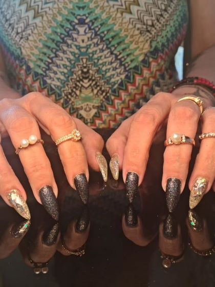A full view of the glamorous black and holographic glitter stiletto nails.