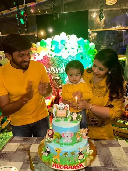 A happy family celebrating their son's first birthday with my two-tier jungle cake.