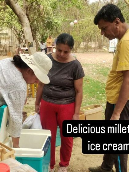 A customer trying a sample of delicious millet ice cream from a vendor's cooler.