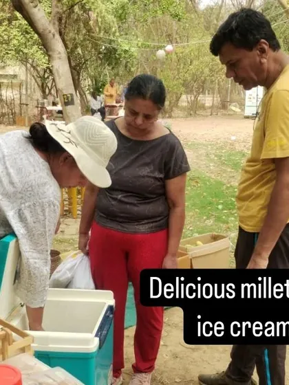 A customer trying a sample of delicious millet ice cream from a vendor's cooler.