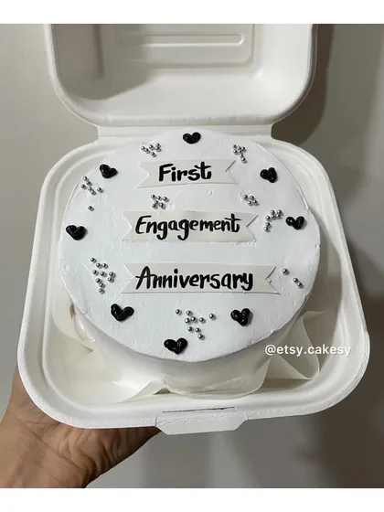 An elegant bento cake to celebrate a 'First Engagement Anniversary', decorated with black hearts and silver sprinkles.