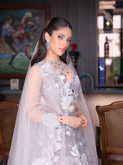 A beautiful portrait of the bride, with her sheer veil creating an ethereal frame. The makeup is elegant and understated, letting the intricate outfit and jewelry make a statement.