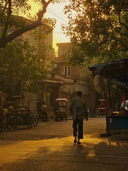 A lone figure walks through a quiet street as the sun sets. This moody, atmospheric shot captures the feeling of a calm evening in the city.