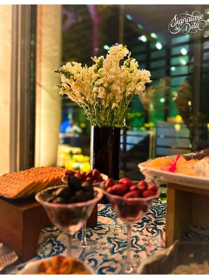 A close-up of the food table, where even the presentation of olives and crackers is considered part of the overall aesthetic, complemented by fresh white flowers.