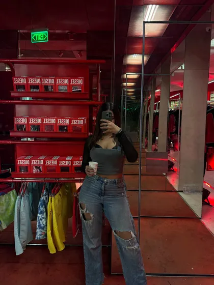 A mirror selfie showing the full relaxed fit of the ripped jeans and layered top.
