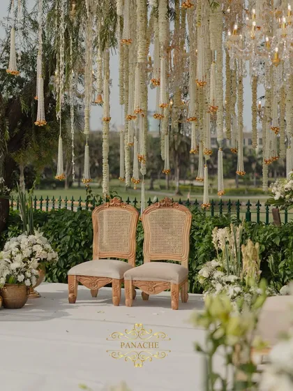 The couple's seating at the mandap, set against a backdrop of hanging floral strings and a view of the golf course. The setting is both intimate and grand.