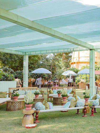 An overview of the relaxed and cheerful Haldi setup. The combination of low seating, wooden furniture, and a soft green canopy created an inviting atmosphere for a day filled with joyful moments.