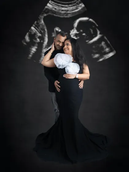 A creative couple's portrait with their baby's ultrasound scan projected in the background. It's a modern and meaningful way to include the newest family member in the photo.