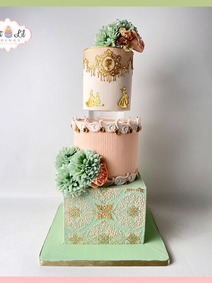 A regal and whimsical tiered cake with a fairytale feel. The design incorporates different shapes and textures, with delicate gold stenciling and pastel colors.