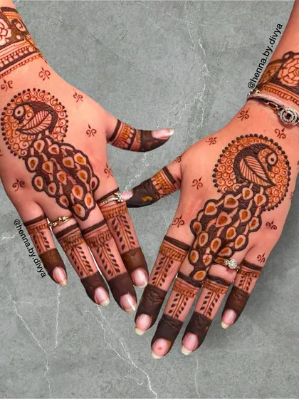 This design highlights the graceful peacock, a symbol of beauty and royalty. The surrounding dots and simple finger patterns make the central motif stand out beautifully.
