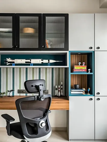 We designed this integrated study area to be both stylish and productive. The setup includes a mix of open and closed overhead storage, with fluted glass doors and dedicated display nooks for personal items, all built around a spacious wooden desk.