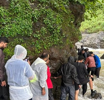 Navigating a tricky, rain-swollen stream during the Kalu Waterfall trek in Maharashtra. Safety is our priority, and our guides use ropes for added security.