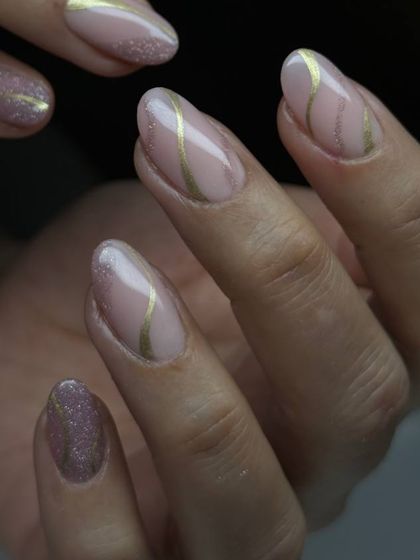 An elegant and artistic design featuring a nude base with delicate gold stripes and a sparkling accent nail. This look is sophisticated with a touch of glamour.
