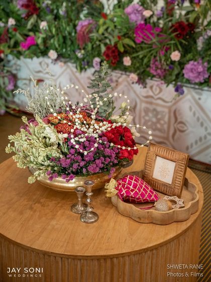 A beautiful tabletop arrangement featuring a vibrant floral centerpiece, silver candle holders, and personalized wedding favors, all curated to match the event's theme.