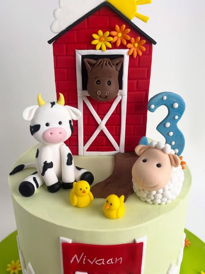 A close-up of the top of the farm-themed cake, showing the handcrafted cow, sheep, horse, and chicks.