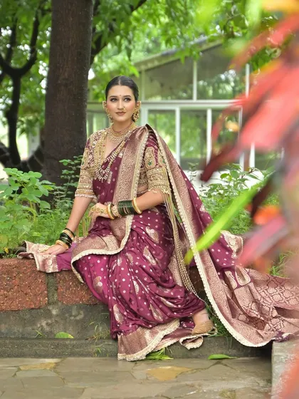 A serene portrait of a Maharashtrian bride in a beautiful garden, her wine-colored Nauvari saree draped perfectly.