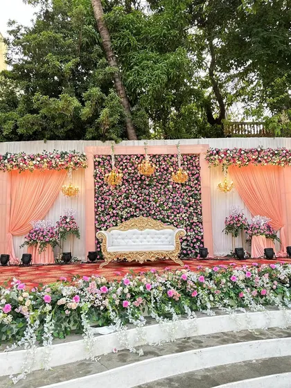 A daytime view of the classic reception stage, showcasing the beautiful peach drapes and the abundance of fresh flowers.