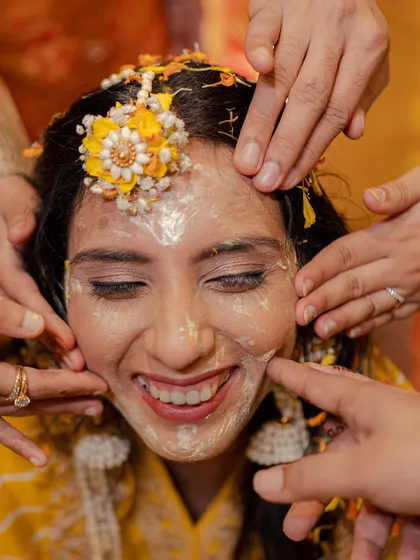 A bride's radiant smile during her Haldi ceremony. Even when covered in paste, her happiness shines through, and we make sure to capture it.