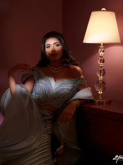 A moody, glamorous portrait of a bride in a stunning structured gown. The single lamp as a light source creates a dramatic, cinematic feel, reminiscent of old Hollywood glamour.