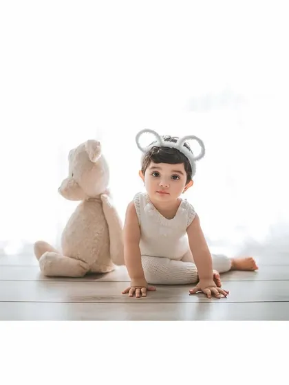 A handsome little mouse posing for his portrait. The all-white outfit and background create a timeless and classic look.