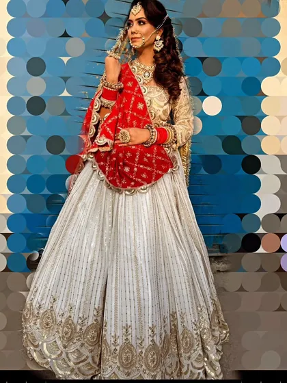 A full-length shot of the elegant white and red bridal lehenga. The striped pattern on the skirt adds a modern touch to the traditional color scheme.