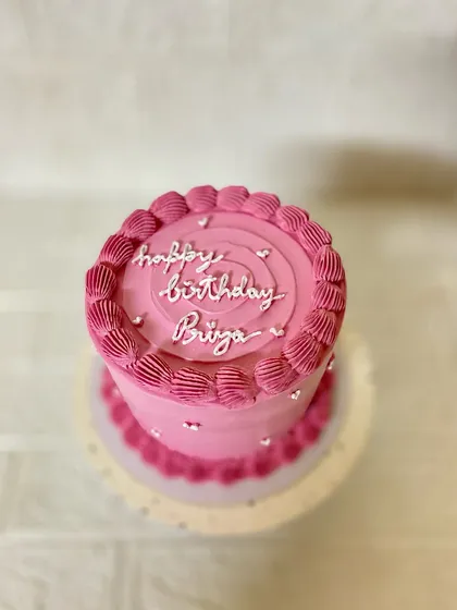 A top-down view of our classic pink birthday cake, showing the swirl details and delicate sprinkles.