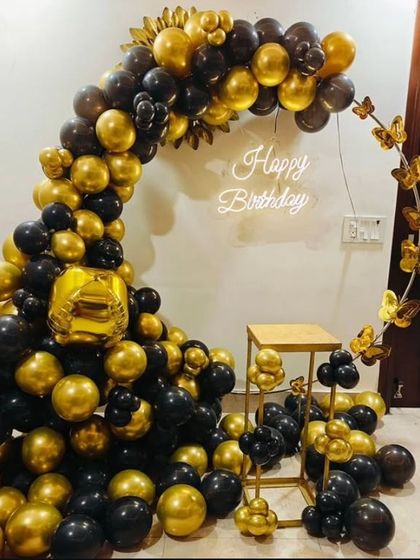 A stylish black and gold balloon ring with butterfly accents and a neon sign.