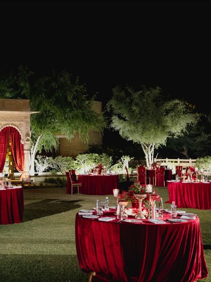 A wider view of the red-themed sangeet setup on the lawns of Suryagarh. The scattered tables created an intimate yet connected feel, allowing guests to enjoy the performances on stage while being immersed in the candlelit, romantic ambiance.
