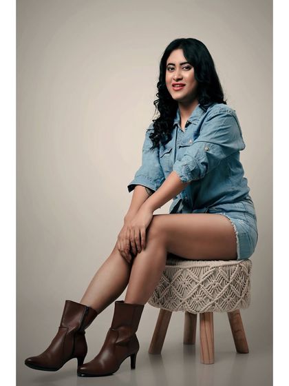 A relaxed and confident studio portrait. The denim-on-denim look and the model's easy smile create a friendly and approachable vibe.