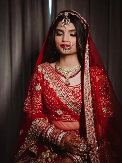 A moment of quiet reflection. The bride's makeup, with its classic red lip and soft glam eyes, looks serene and beautiful.