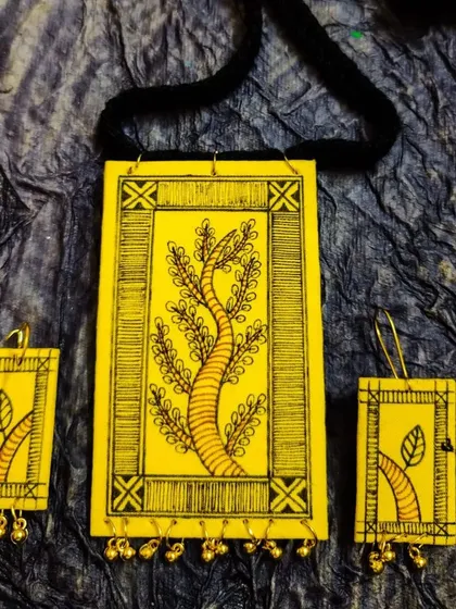 This hand-painted set is inspired by the 'Tree of Life' motif found in many folk traditions. I've used a bright yellow fabric base to make the intricate black line-work stand out. Tiny ghungroos add a delicate sound to this nature-inspired artisan jewelry set.
