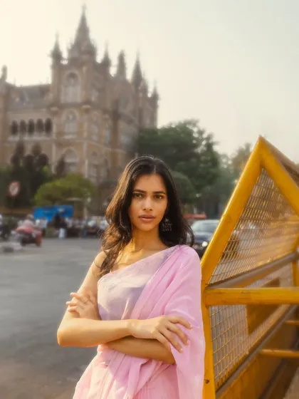 A powerful stance in front of the iconic Chhatrapati Shivaji Maharaj Terminus. The yellow barricade adds a pop of color and a gritty, urban feel.