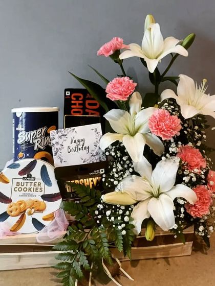 This elegant hamper features a lovely bouquet of white lilies and pink carnations. It's paired with butter cookies, chocolates, and other treats, making it a perfect birthday or thank you gift.