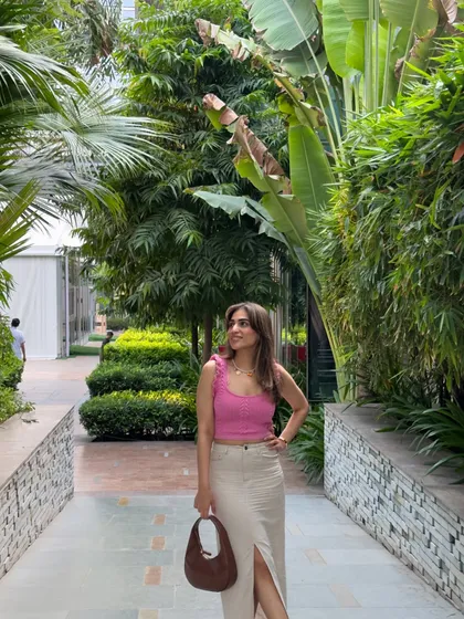 A full-length view of the pink top and linen skirt combo. The slit in the skirt adds a modern touch.